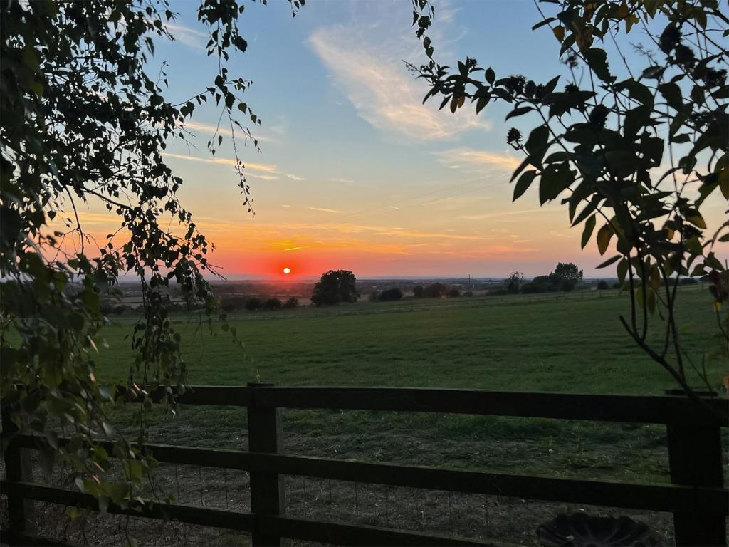 um pôr-do-sol sobre um campo com uma cerca em Blackhills Barn em Northallerton