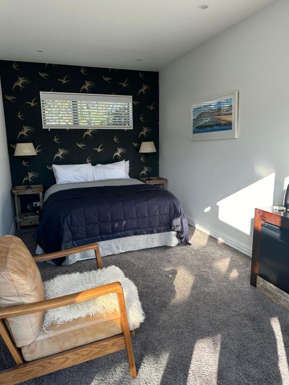 a bedroom with a bed and a chair at Guest Suite St Clair Beach in Dunedin