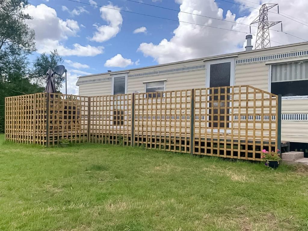 a wooden fence in front of a house at Otters Retreat in Fernhill Heath