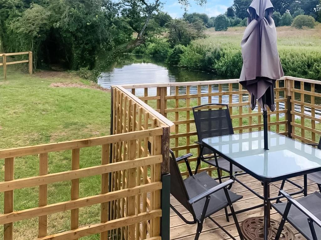 una mesa y sillas en una terraza con vistas al río en Otters Retreat en Fernhill Heath