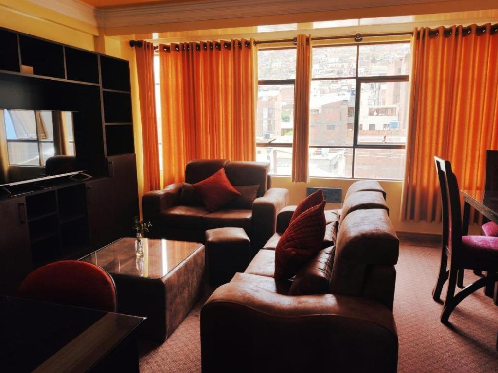 sala de estar con sofá, sillas y TV en COMODORO DEPARTAMENTOS en Oruro