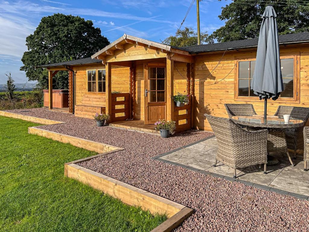 a wooden cabin with a table and an umbrella at Stable Lodge At Greenacre in Bromyard