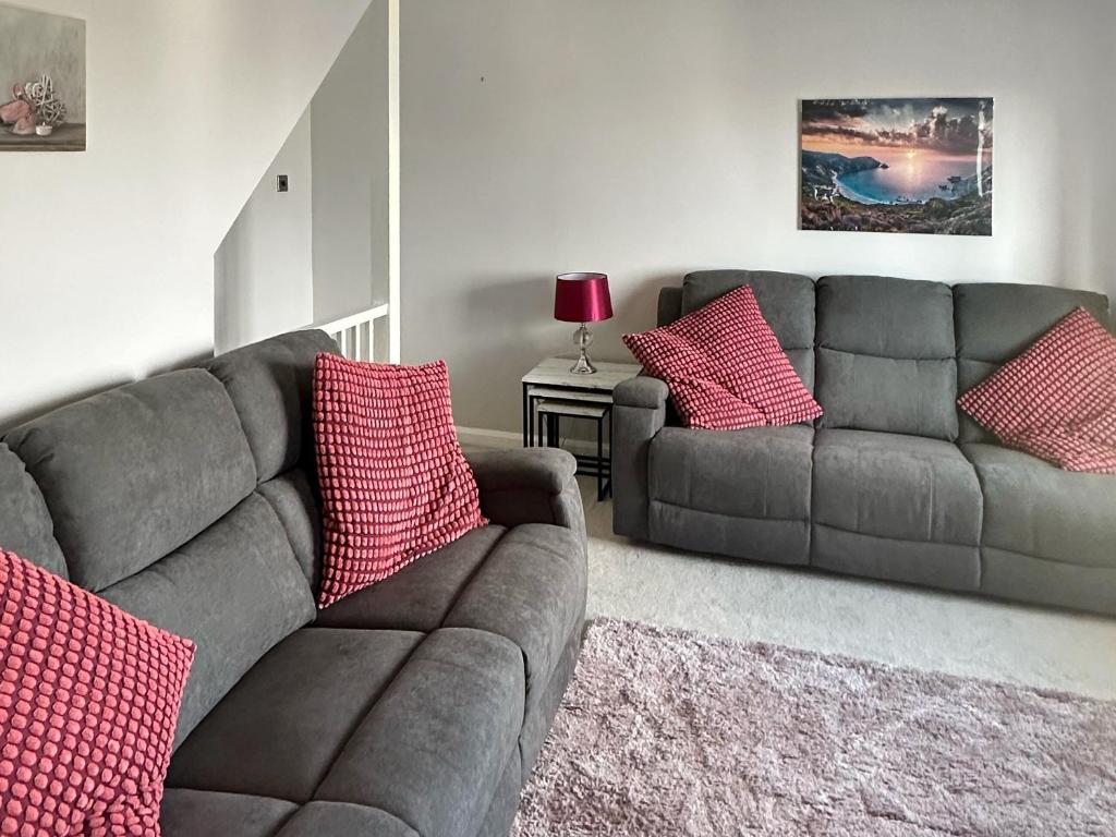 sala de estar con sofá gris y almohadas rojas en Cousens House en Dawlish