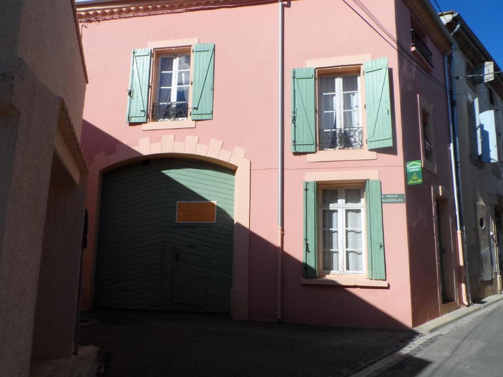 a pink building with a garage and two windows at Clos Mazerolles in Cruzy