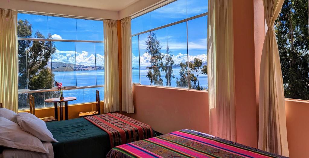 een slaapkamer met een groot raam met uitzicht op het water bij Amantani Samary Lodge in Ocosuyo