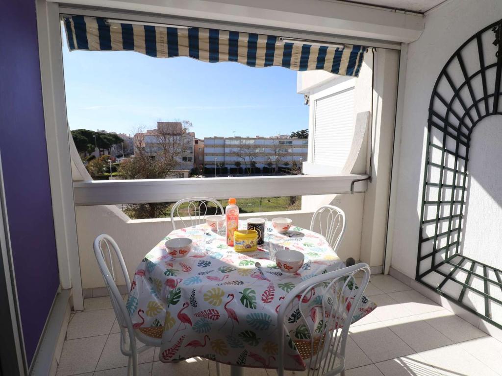 une table et des chaises assises sur un balcon avec une fenêtre dans l'établissement Appartement 2 pièces climatisé avec parking, proche plage - FR-1-307-254, au Grau-du-Roi