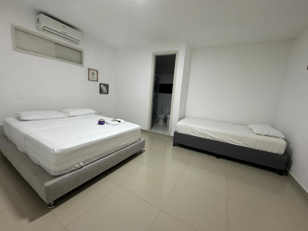 two beds in a room with white walls at Hotel Balcones del Sinu in Lorica