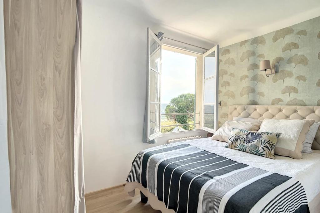 Schlafzimmer mit einem Bett und einem Fenster in der Unterkunft Charming Provencal studio with a large swimming pool and a view of the hill in Montauroux