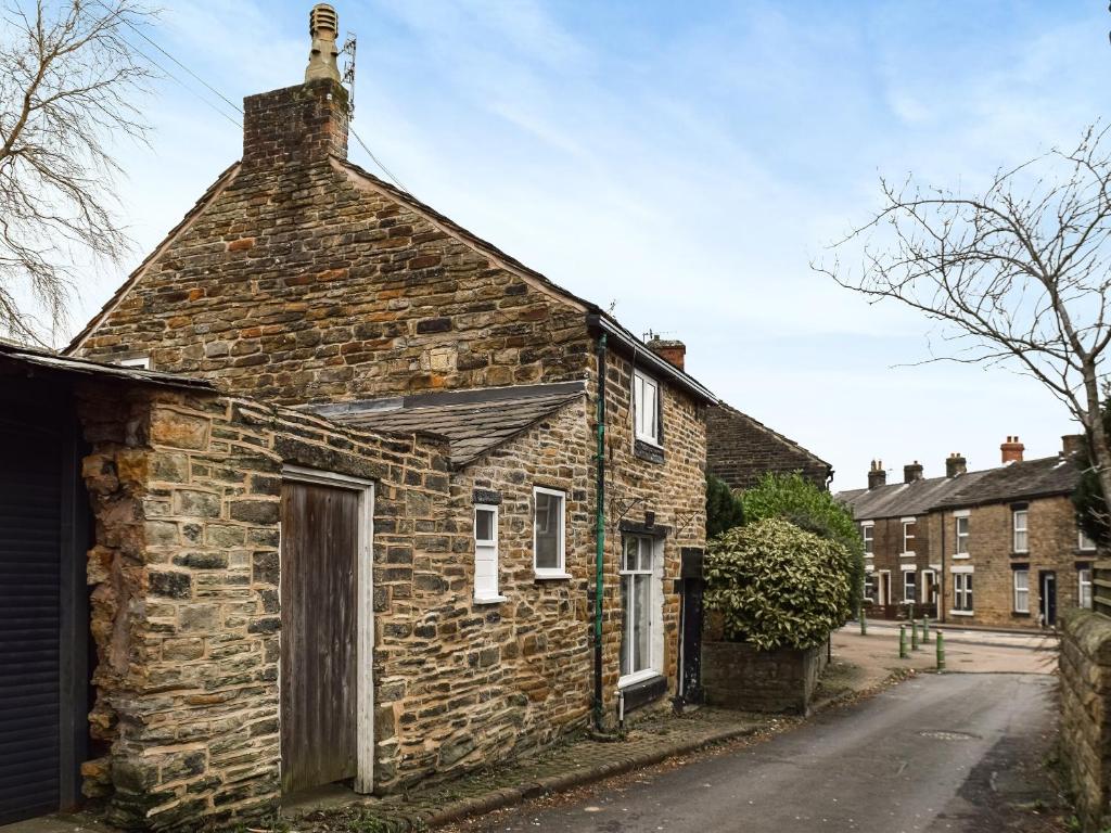 an old brick house with a chimney on a street at Ye Olde Mottram Chip Shop in Glossop