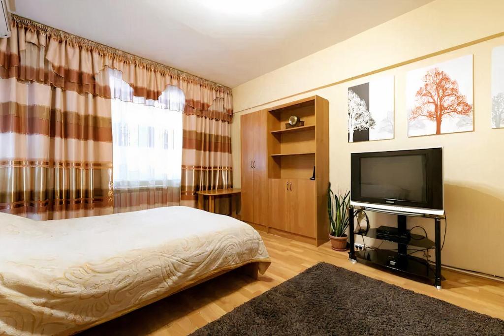 a bedroom with a bed and a flat screen tv at Nadezhda Apartments on Zhibek Zholy Avenue 33 in Almaty