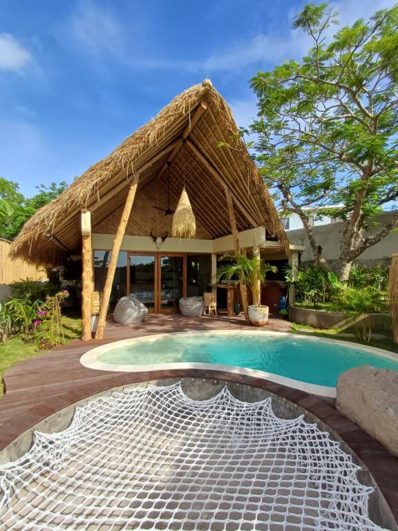 un complejo con piscina y techo de paja en Lodge tropical Fullmoon, en Uluwatu