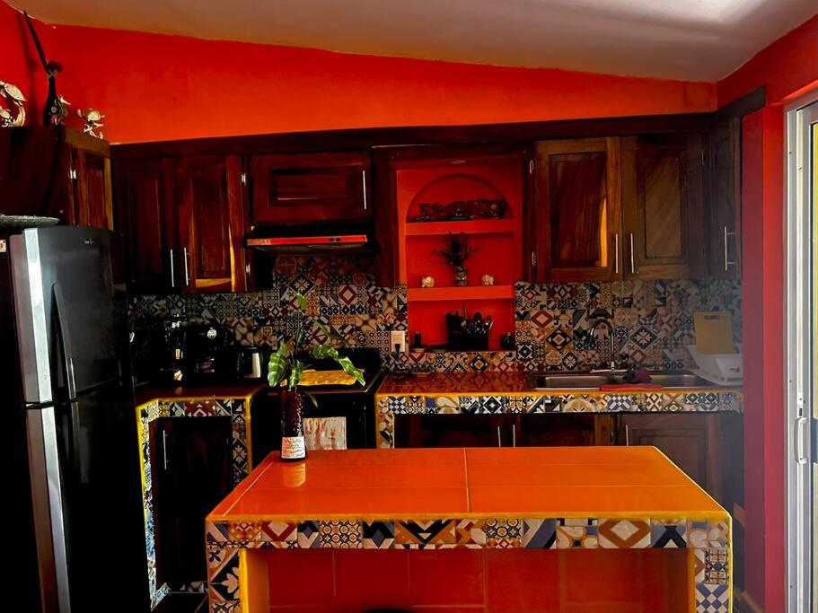 a kitchen with red walls and a black refrigerator at Departamentos “Ama” in Puerto Vallarta