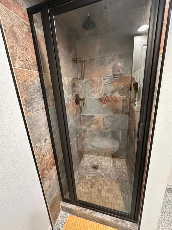a shower in a bathroom with a glass door at Basement Bliss: Cozy Getaway in Cheyenne