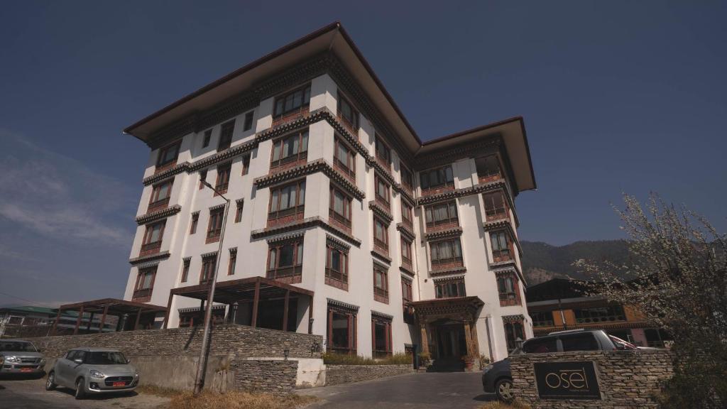 un gran edificio blanco con coches estacionados frente a él en Osel Thimphu Bhutan en Thimphu