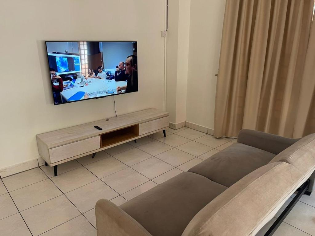 sala de estar con sofá y TV de pantalla plana en Pelangi Indah 8 Rooms Corner Pool Table en Ulu Tiram
