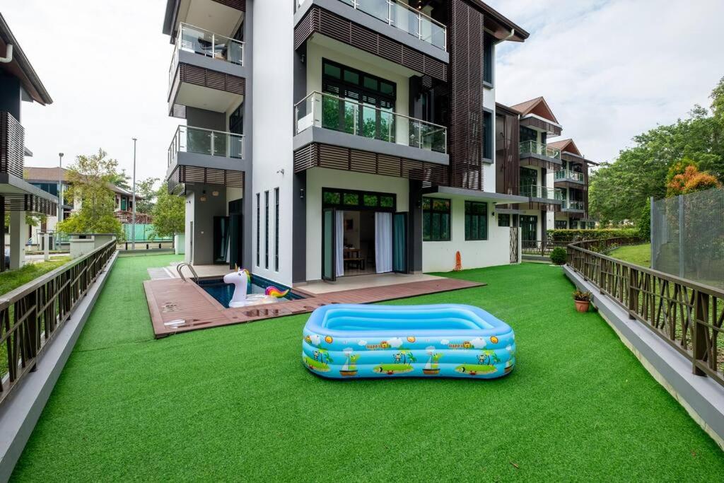 un edificio con césped verde con una maleta. en Bungalow Putrajaya 15pax w Private Pool Gathering, en Putrajaya