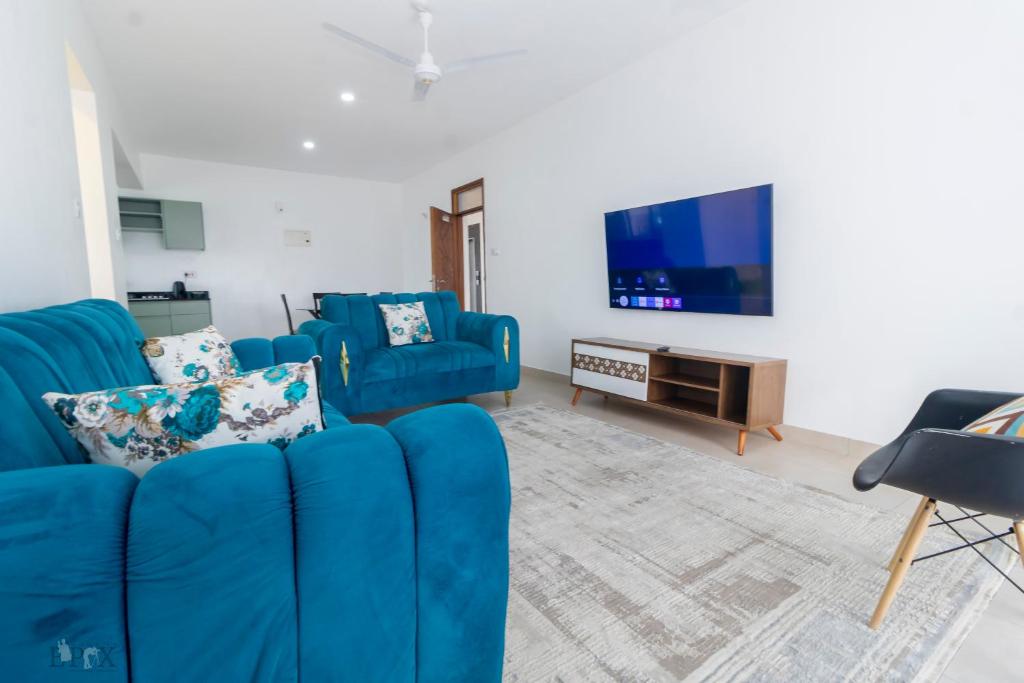 a living room with a blue couch and a tv at Elegant and classy stay in Shanzu