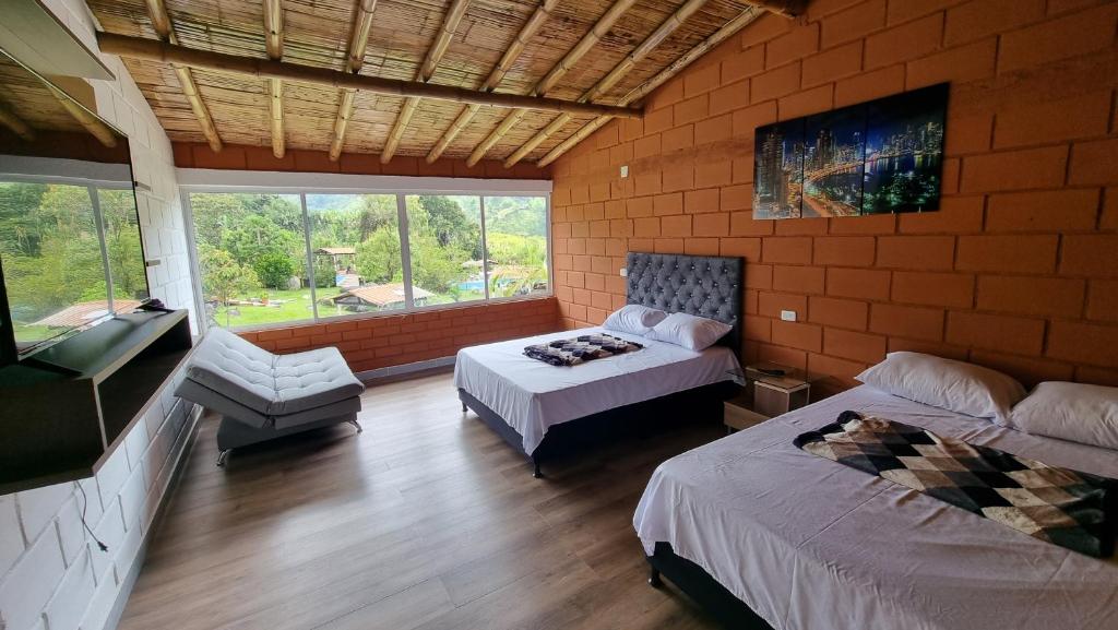 Un dormitorio con 2 camas y una silla. en Cabaña del lago, en Cocorná