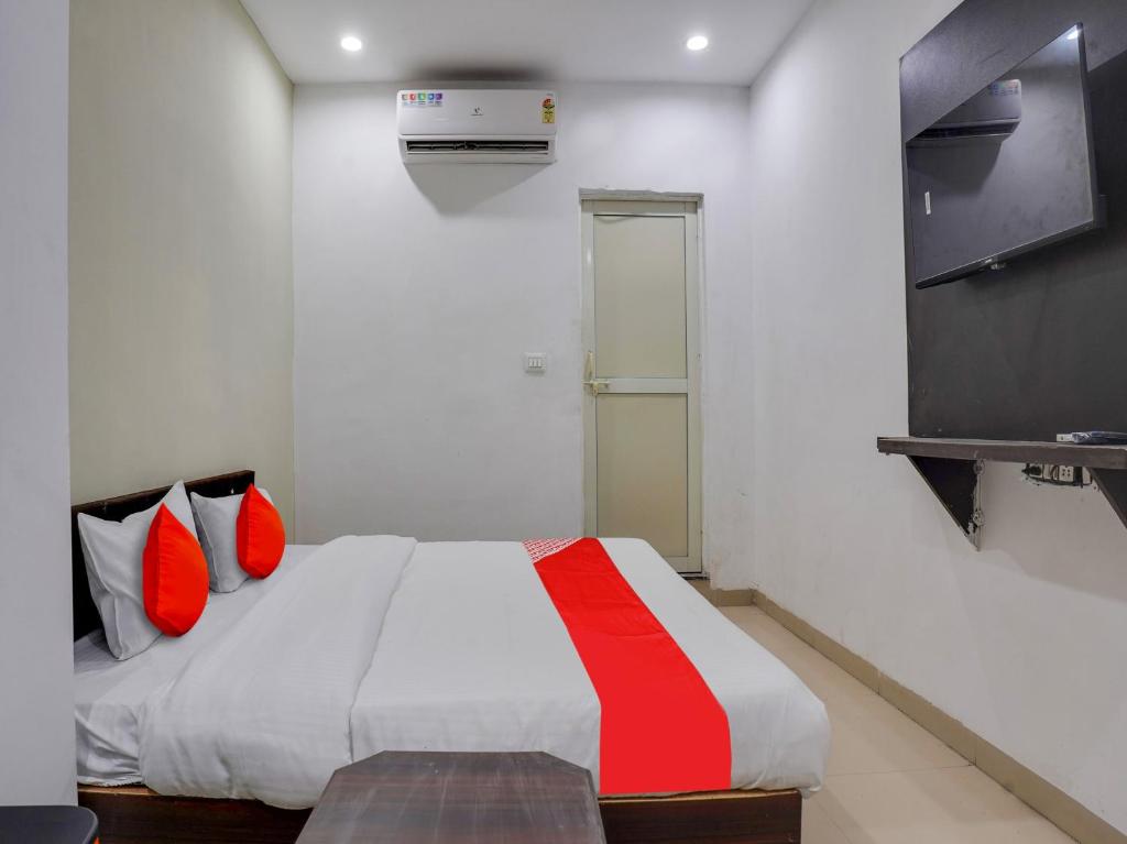 1 dormitorio con 1 cama con almohadas rojas y TV en OYO Flagship Hotel Golden Cheery en Bhopal