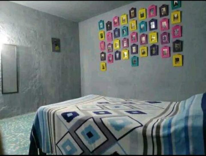 Schlafzimmer mit einem Bett mit einer Bettdecke und einer Wand mit Bildern in der Unterkunft Posada Hortencia in La Huerta