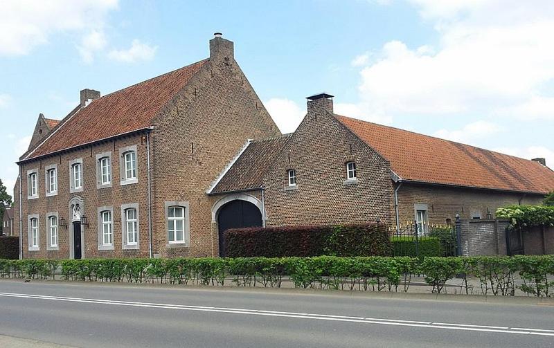 ein großes Backsteingebäude mit rotem Dach in der Unterkunft Hoeve de Hoge Swaen in Maastricht