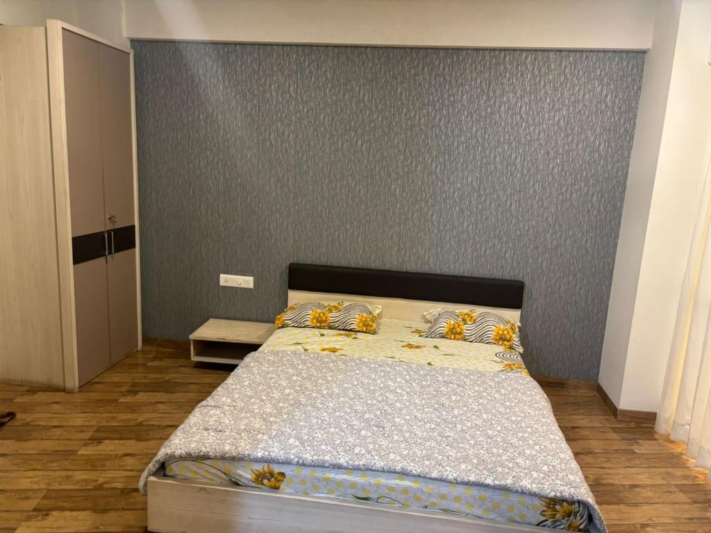 a bedroom with a bed with a gray wall at Rajhans Belizia JSM in Surat