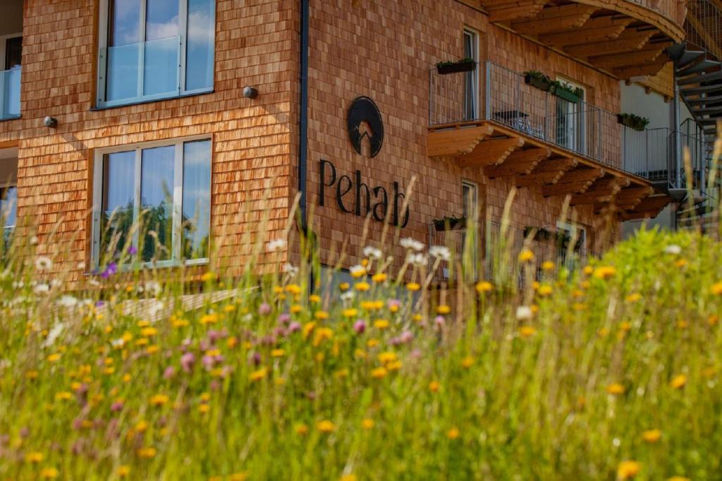 a brick building with a field of flowers in front of it at Aktivhotel Pehab in Ramsau am Dachstein