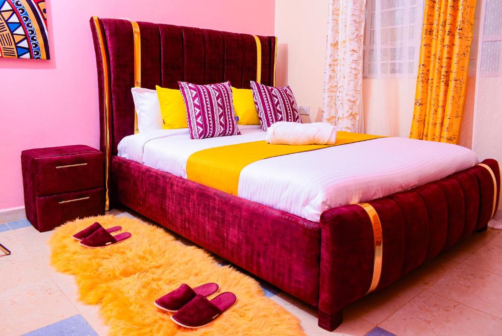 a bedroom with a large bed with purple slippers on the floor at Ruby Modern Homes Nyeri-Skuta in Nyeri