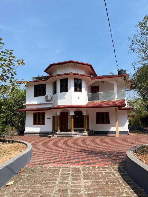 a large white house with a brick driveway at Souparnika Homestay in Kannur