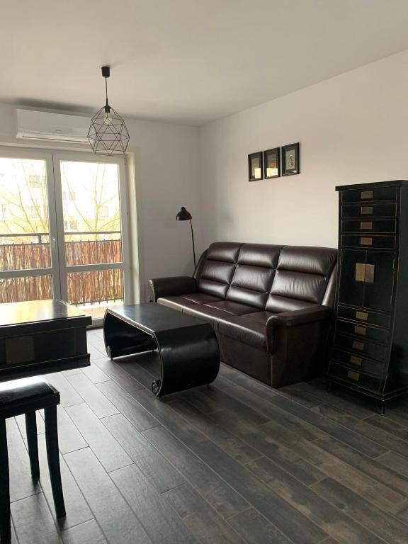 a living room with a leather couch and a table at Apartament Jędrzejów in Jędrzejów