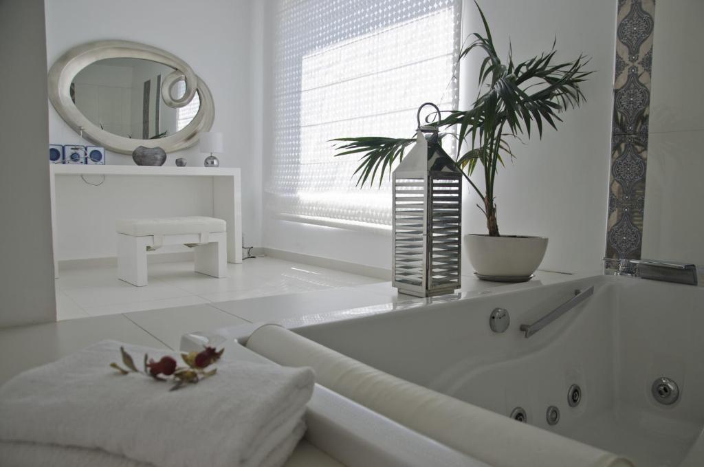 a white bathroom with a tub with a plant on it at Reveli Estate in Kalathas