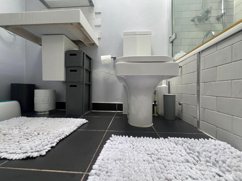 a bathroom with a toilet and a white rug at My Sky LDN Secret Garden in London