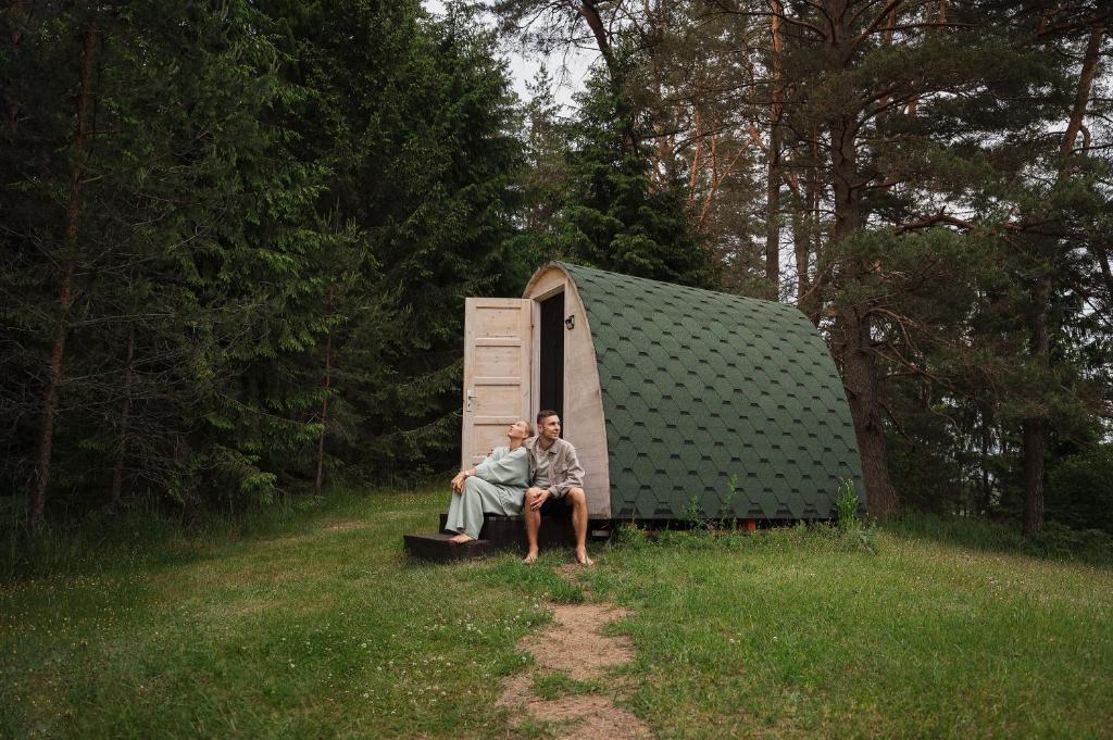 Kaltanėnai的住宿－Miško Maudynės，两人坐在帐篷前的长凳上