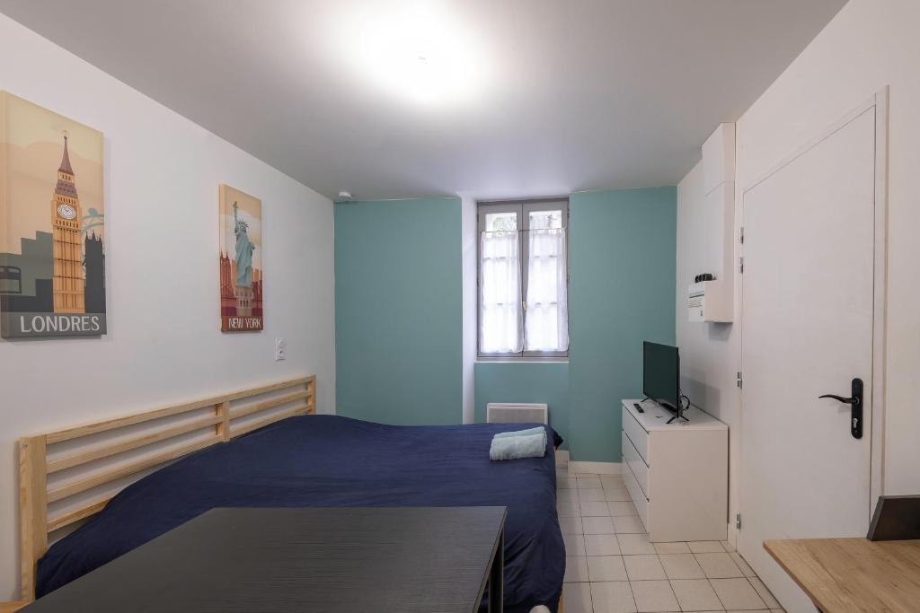a bedroom with a blue bed and a television at le p'tit studio de Segré centre in Segré
