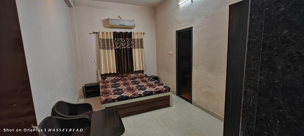 Habitación pequeña con cama y sillas. en Shri mallick Mangalam en Korba