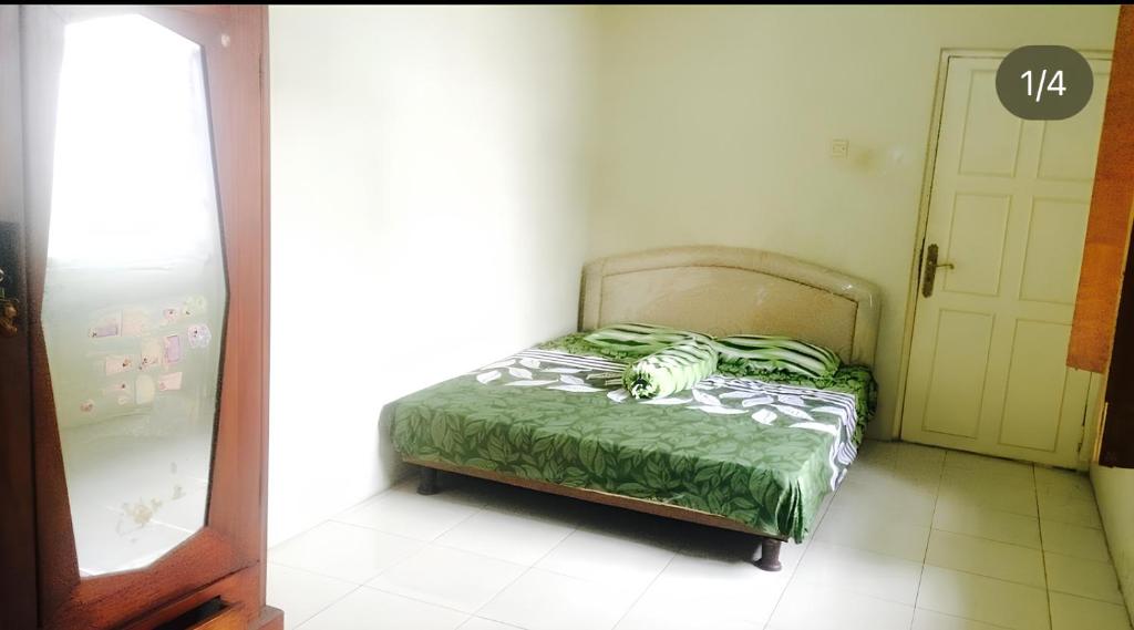 a bedroom with a bed with a green comforter at Rumah Kost 10 Gambir in Jakarta