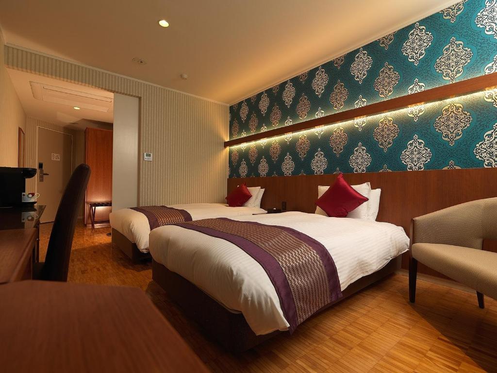 a hotel room with two beds and a television at La Jolie Motomachi in Hakodate