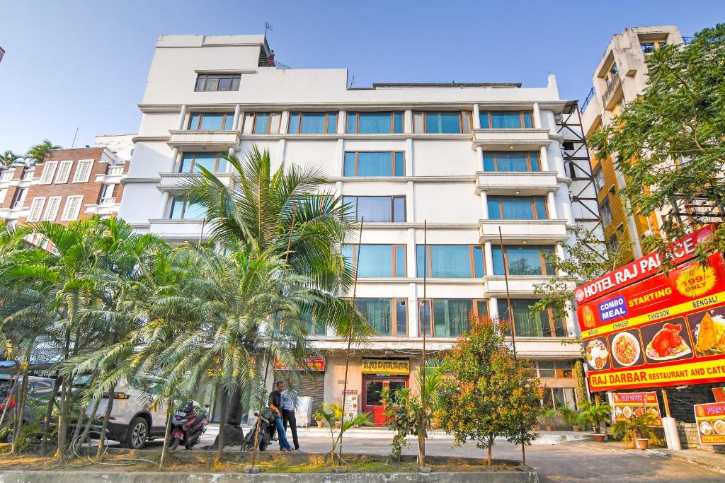 a tall white building with palm trees in front of it at Brill Raj Palace Near City Centre 2 in kolkata