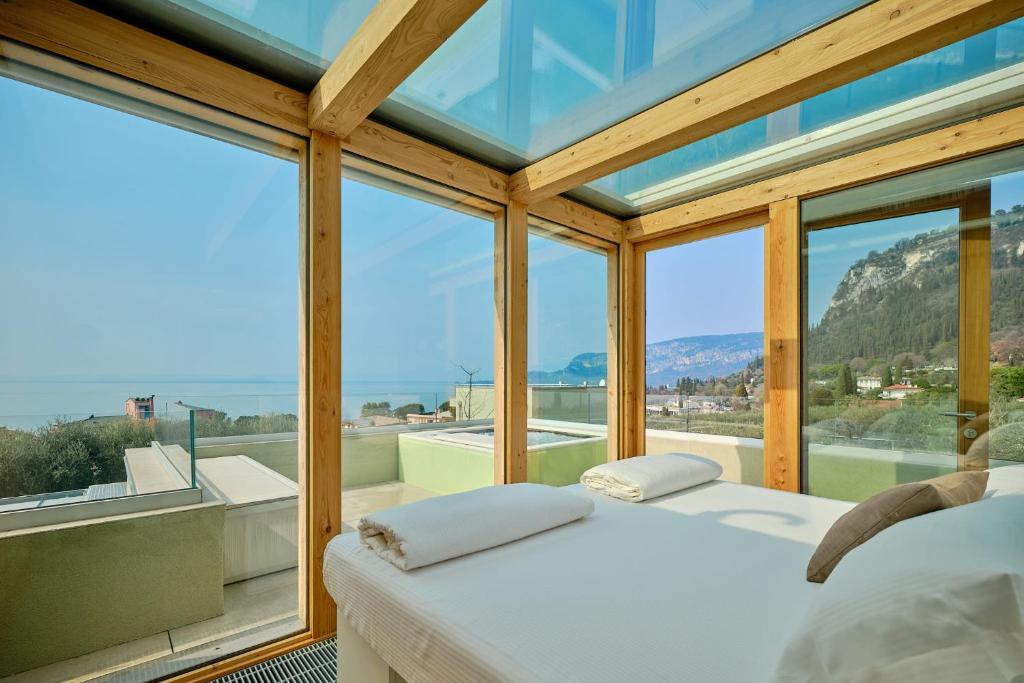 a bedroom with a bed and large windows at Villa Sunny Lake Suites in Bardolino