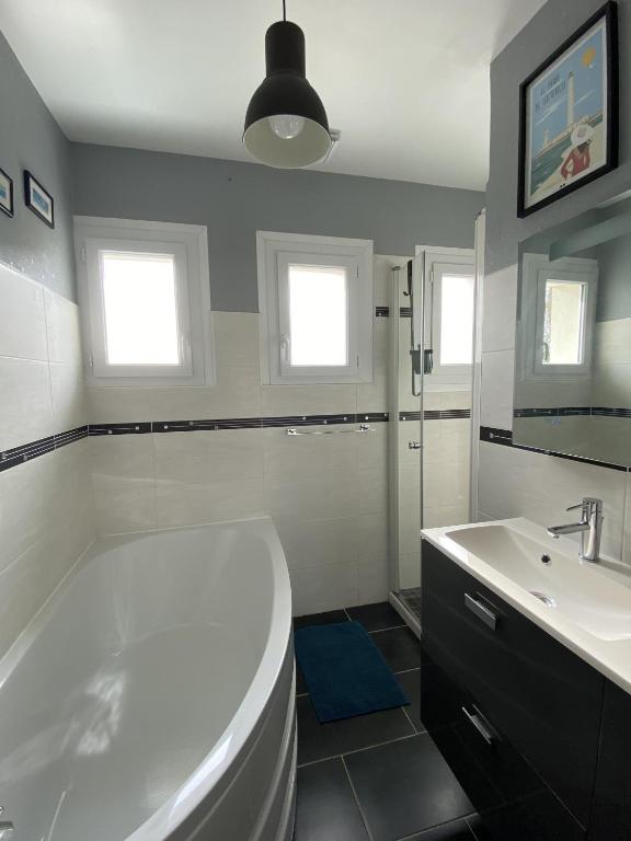 a white bathroom with a tub and a sink at La Maison des phares in Lion-sur-Mer