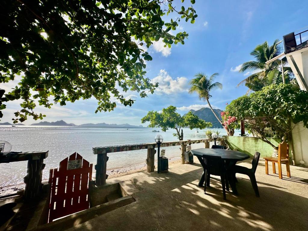 a table and chairs sitting next to a beach at Desert Rose Beach Hotel in El Nido