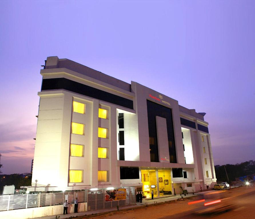 een groot wit gebouw met gele ramen aan een straat bij Peerless Hotel Hyderabad in Hyderabad