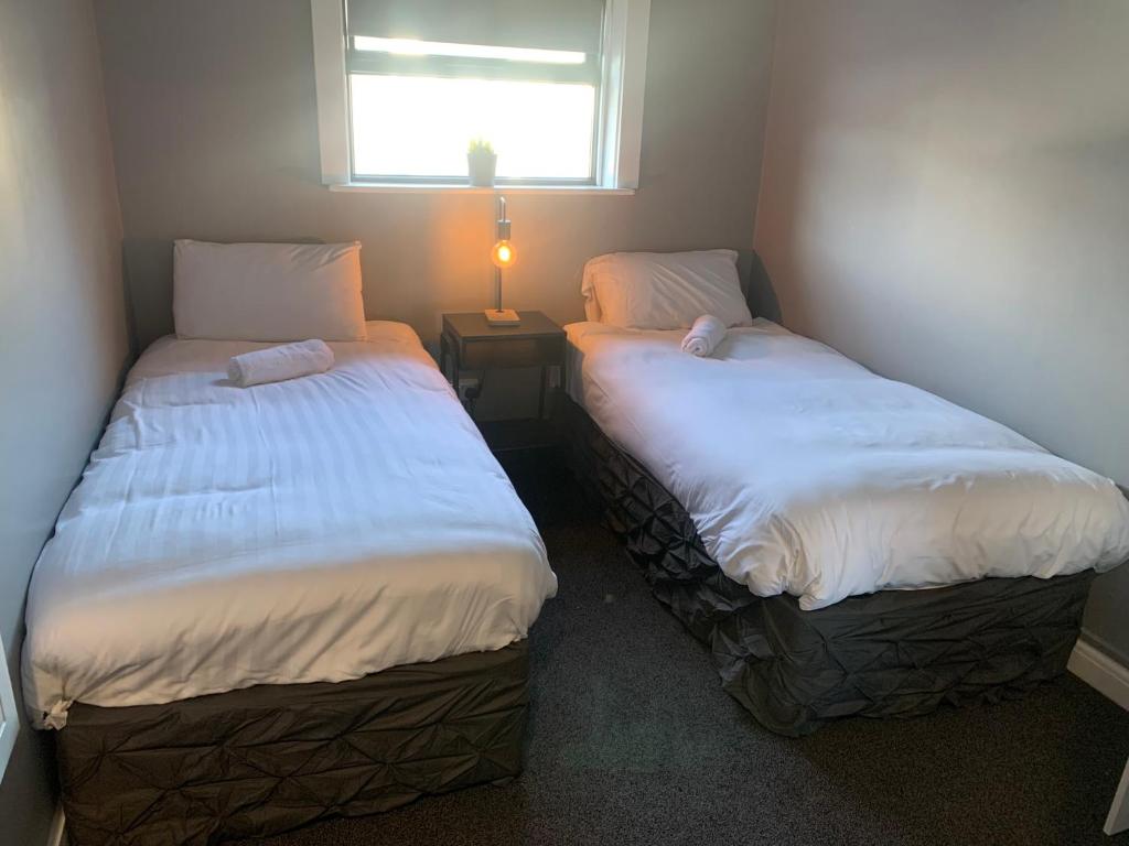 two beds in a small room with a window at Twelve - Boutique Guest House -Galway City Centre -6 Bed En-Suite - Free Parking in Galway