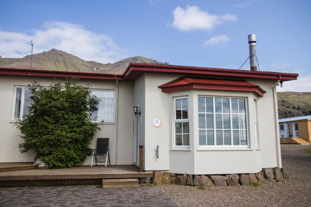 a small white house with mountains in the background at Berunes HI Hostel in Berunes