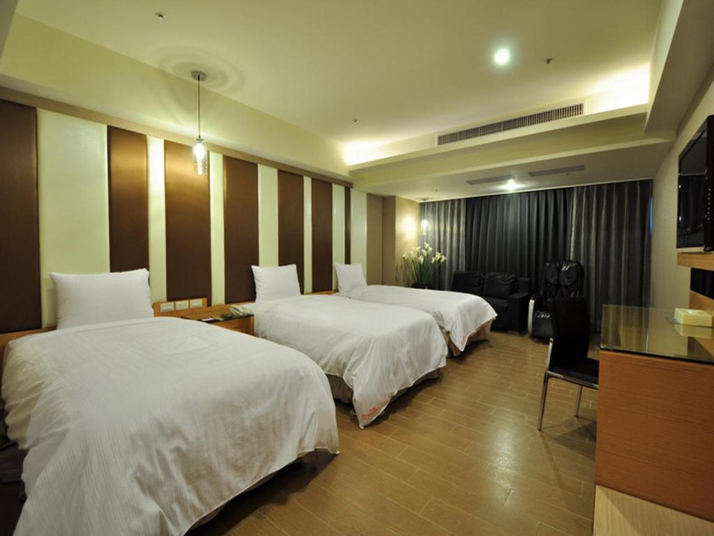 a hotel room with two beds and a table at Goodness Plaza Hotel in Taishan