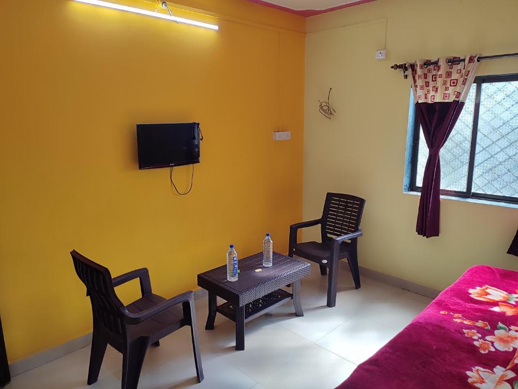 Habitación con mesa, 2 sillas y TV. en Shri Krupa Homestay, en Diveagar