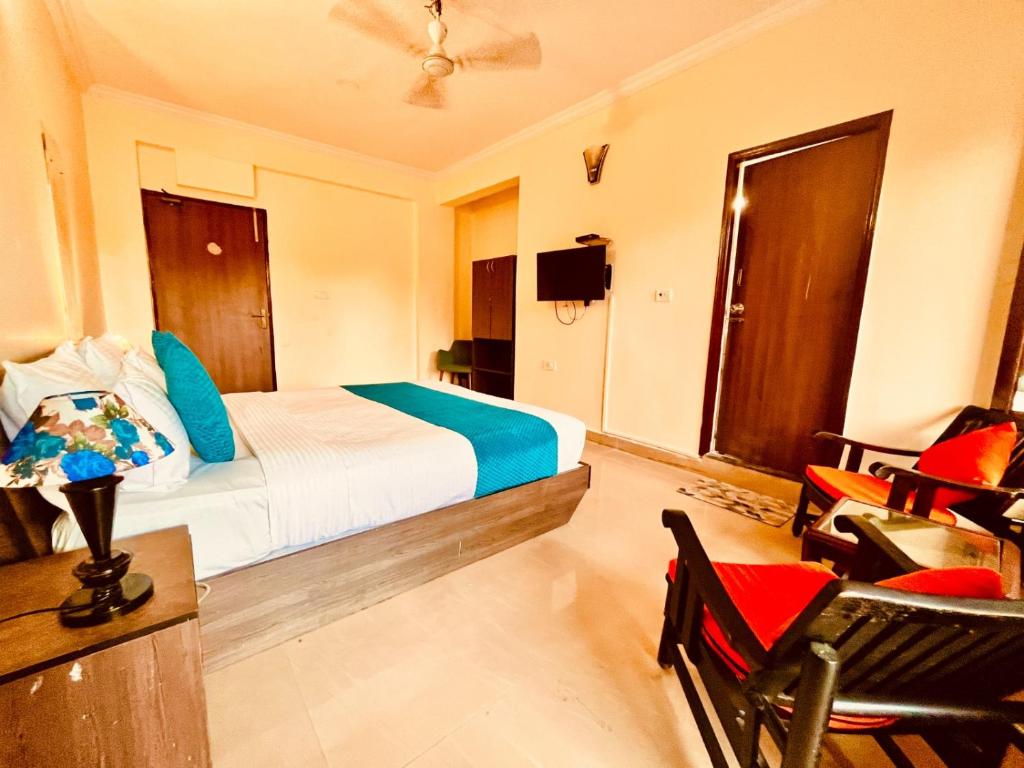 a bedroom with a bed and a desk and chairs at Hotel Shivam Inn - Near Calangute Beach in Calangute