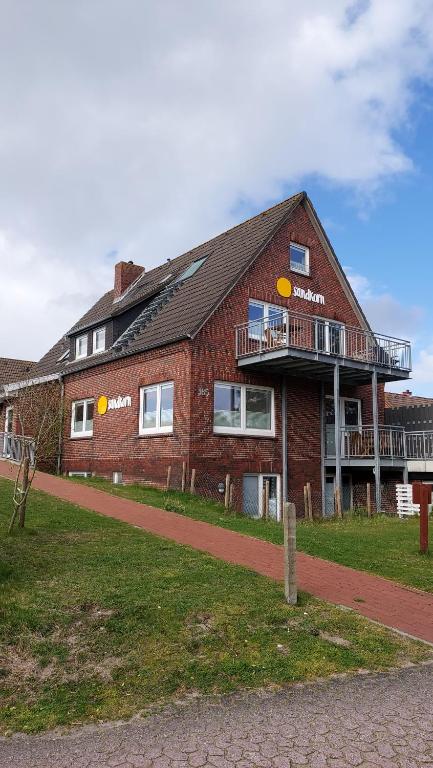 a brick building with a balcony on the side of it at Haus Sandkorn in Baltrum