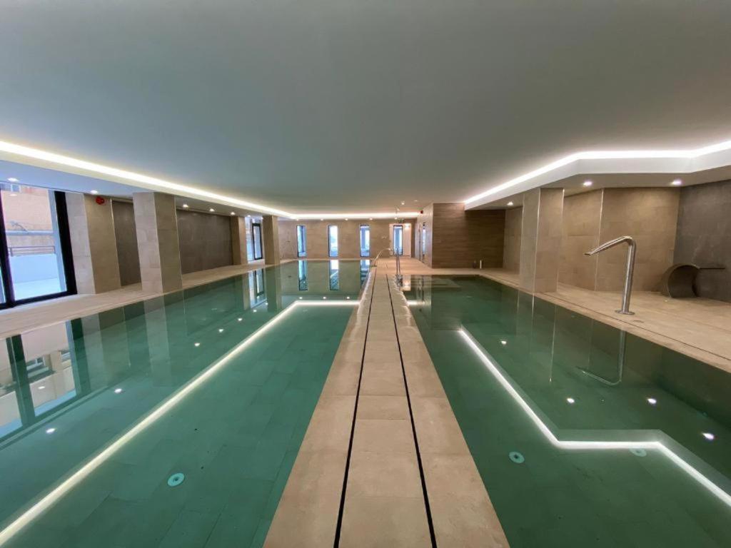 a large swimming pool with green water in a building at CP Top floor luxury studio with spa and pool in Gibraltar