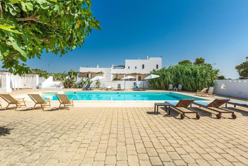 Una piscina con tumbonas al lado de una casa. en Masseria Pepe, en Torre Ovo